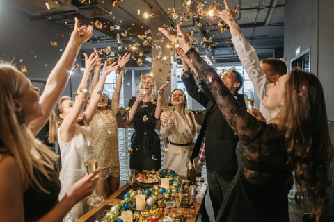 Office party scene with people throwing gold confetti around a table of food