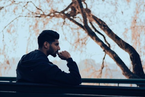 a man sits on a bench in a thoughtful pose