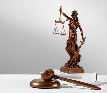 Judges gavel and small statue of woman holding legal scales and sword.