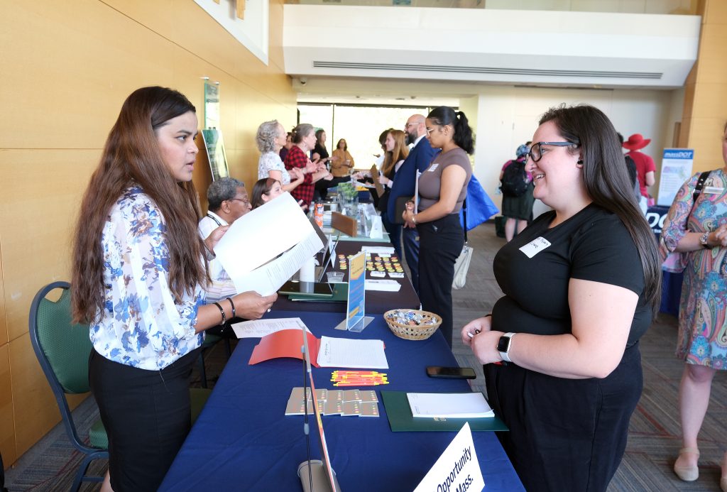 Image of a career fair, in the foreground a job seeker and an employer are talking