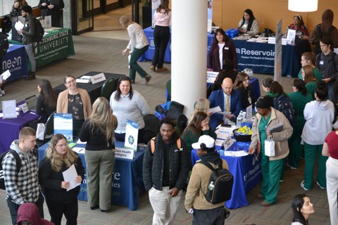 Many people stand at booths at a career fair event.