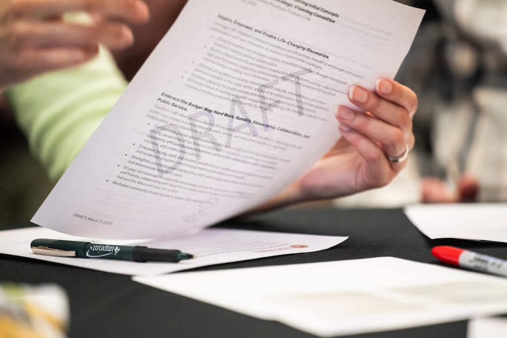 A draft document is held up as faculty and staff discuss and provide feedback on the Visioning Committee’s initial concepts to help inform recommendations for the university’s next strategic framework during a Strategic Visioning Community Conversation held in the Gordon Dining and Event Center at the University of Wisconsin–Madison on April 16, 2025. (Photo by Jeff Miller / UW–Madison)