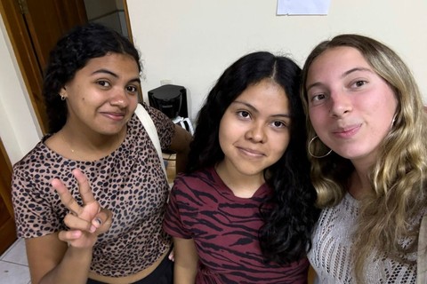 Three young women take a selfie together and smile into the camera.