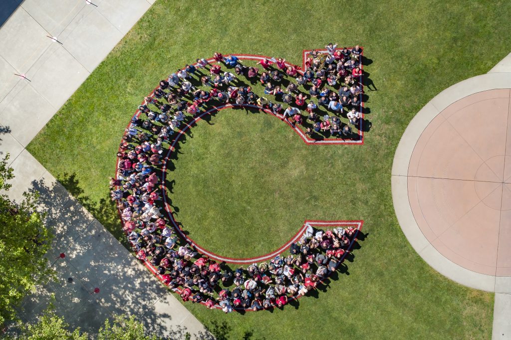 A group of students standing together to form a large letter “C".
