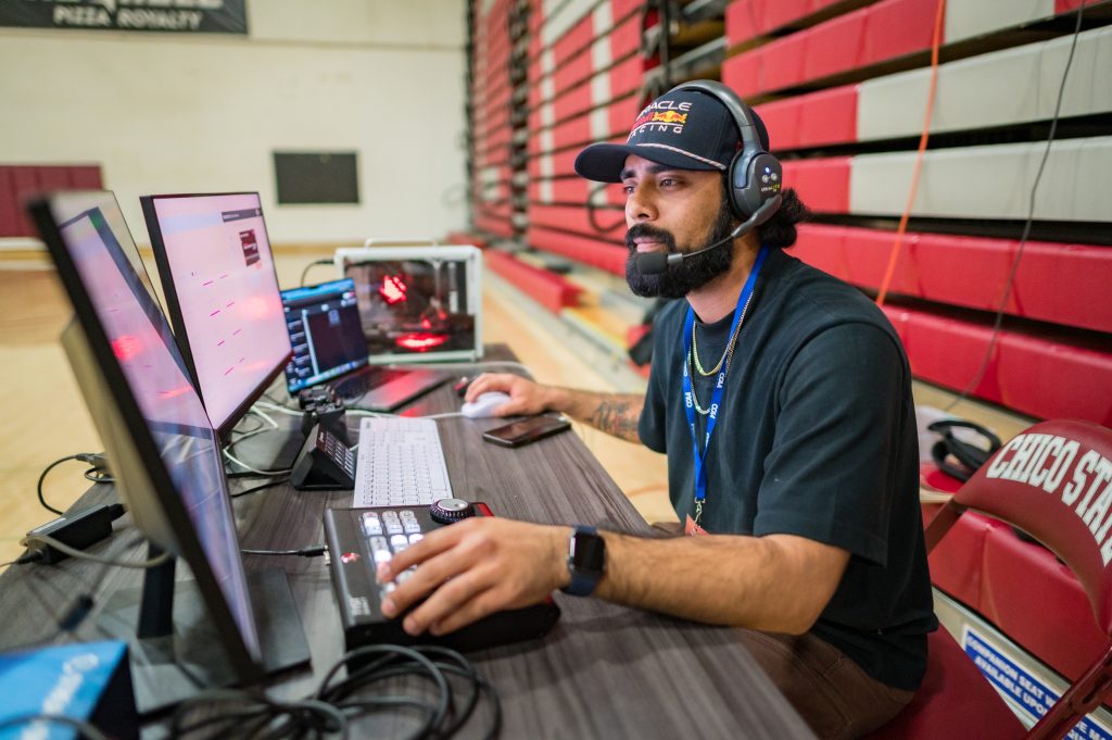 A student wearing a headset while looking at two screen monitors.