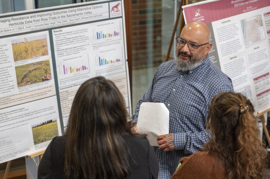 An employer holding a sheet of paper in his hands while networking with two students. 