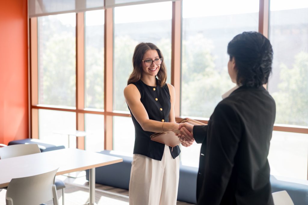 A student smiles and shakes hands with an employer.