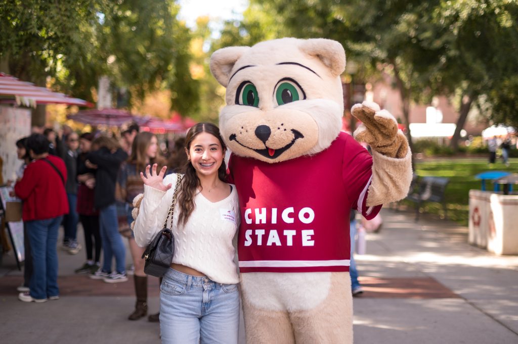 A student poses with the Chico State mascot Willie the Wildcat.