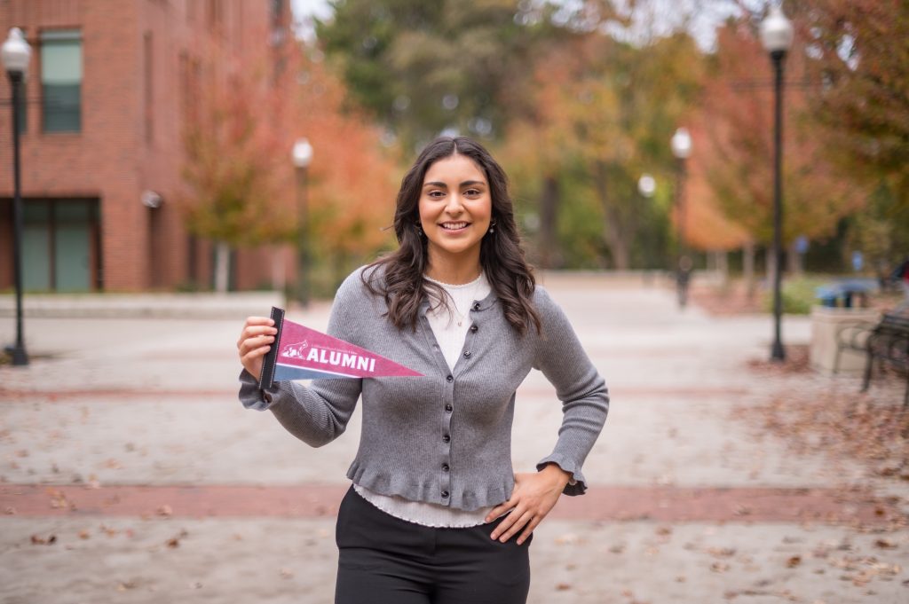 A student is holding a Chico State alumni pennant.