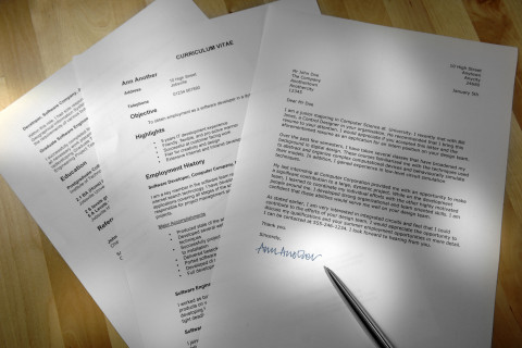 A cover letter and resume on a table with a pen.