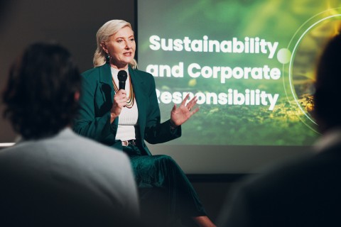 Speaker presenting at a meeting. The presentation says Sustainability and Corporate Responsibility.