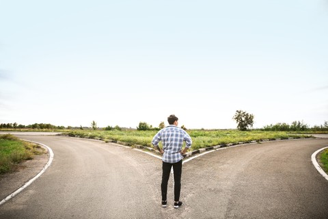 Stock photo of a person contemplating a fork in the road, representing career paths